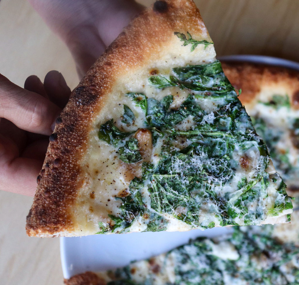 someone holding up a slice of pizza